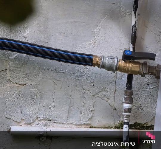 צינור מים עם ברז על קיר חיצוני